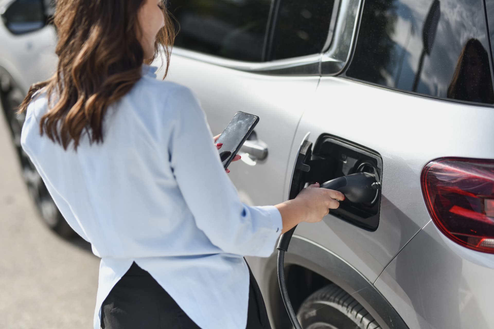 Woman charging an electric vehicle